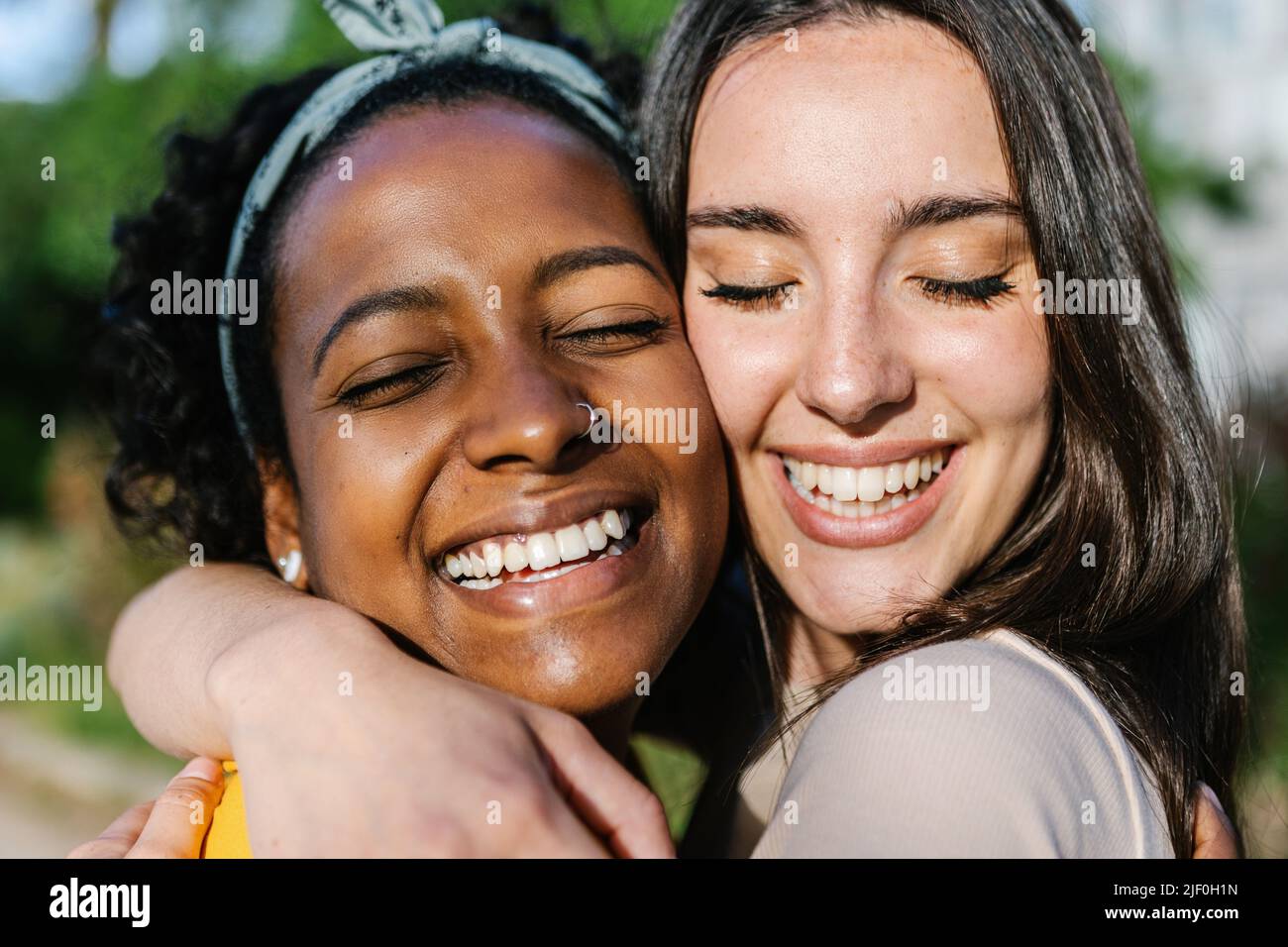 Candid happy multiracial best women friends embracing outdoors Stock Photo