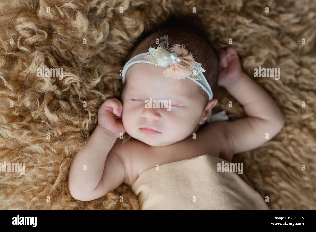Cute newborn baby sleeping on brown fur blanket. Baby goods packaging