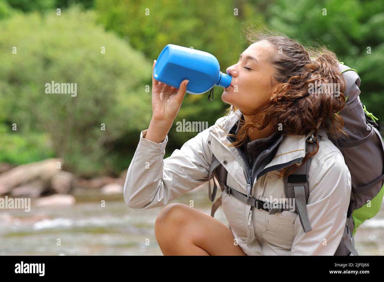 Side view portrait of a tekker drinking water from bottle in a river Stock Photo