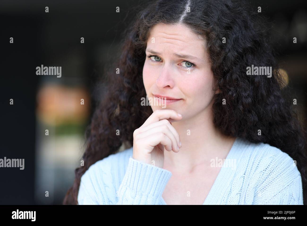 Portrait of a suspicious woman looking at camera in the street Stock Photo