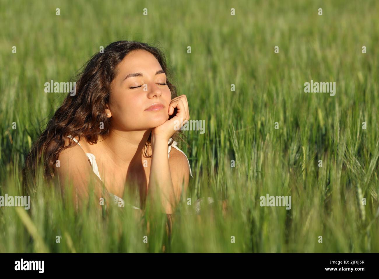 Woman breathing fresh air and relaxing in a green wheat field Stock Photo
