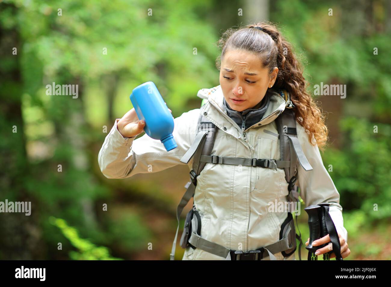 Trekker worried with empty water bottle alone in a forest Stock Photo