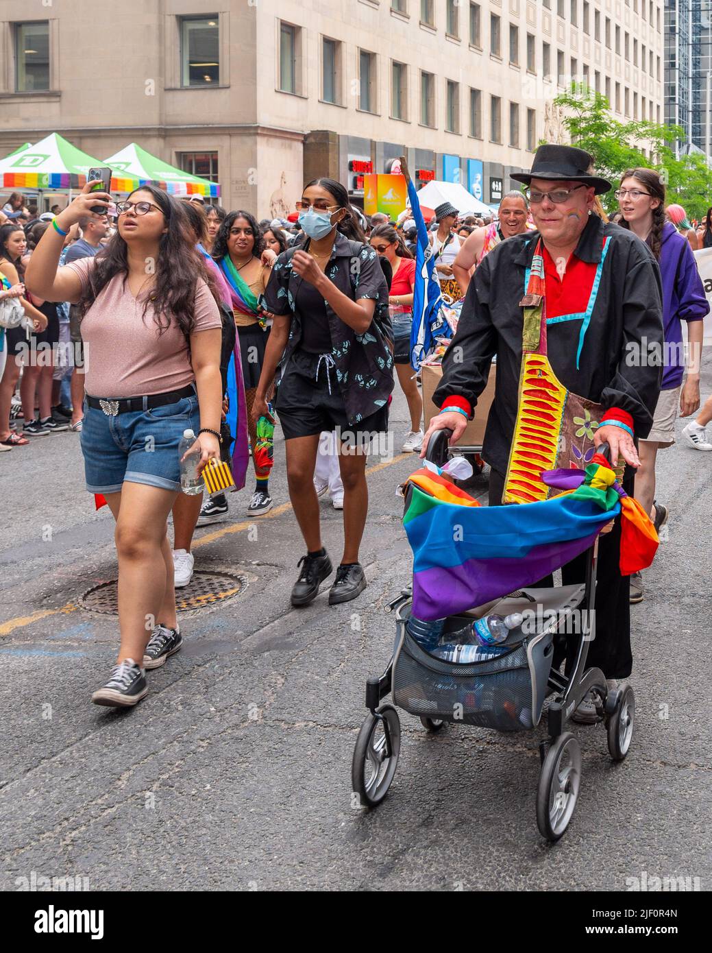 Senior man in a walker walks alongside other people during the Pride Parade in Bloor Street. Stock Photo