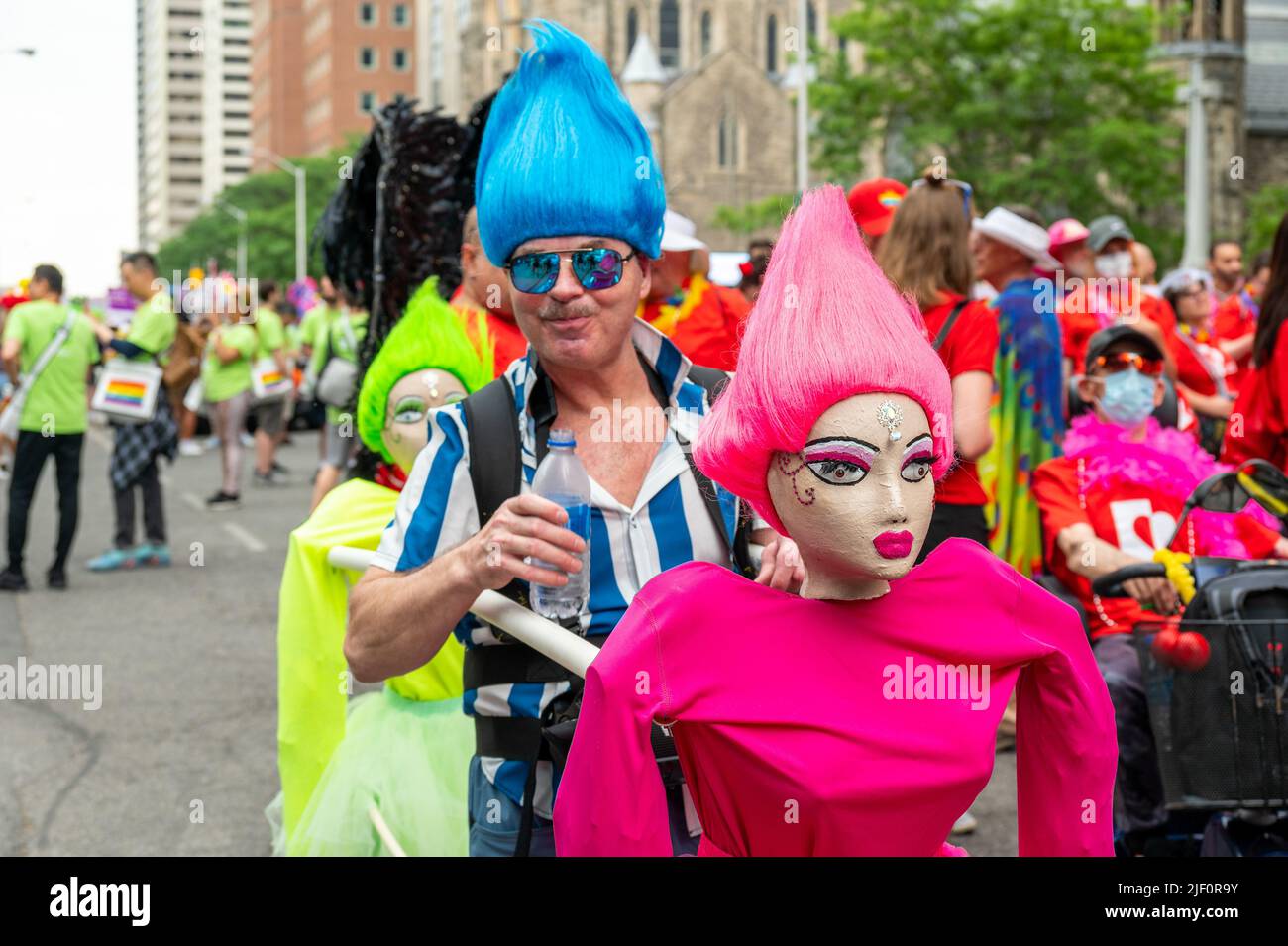 A person marching with two dolls in Bloor Street during Pride Parade Stock Photo