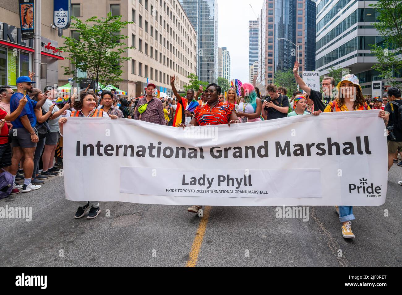 Group of people behind a banner announcing Lady Phyll as International Grand Marshal. They are marching in Bloor Street during Pride Parade Stock Photo