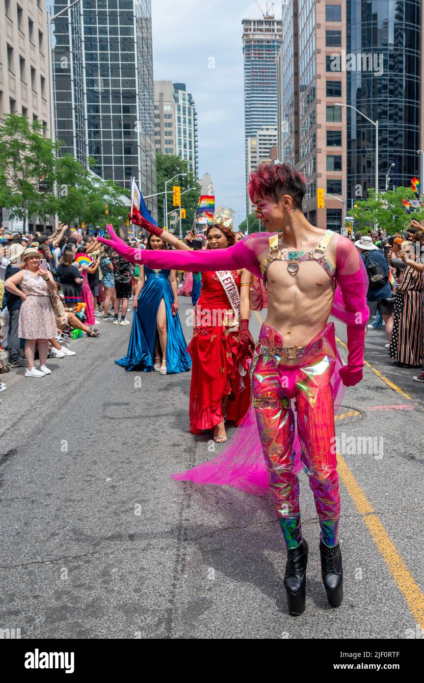 A young man wearing stage custom marching in front of a group during Pride Parade Stock Photo
