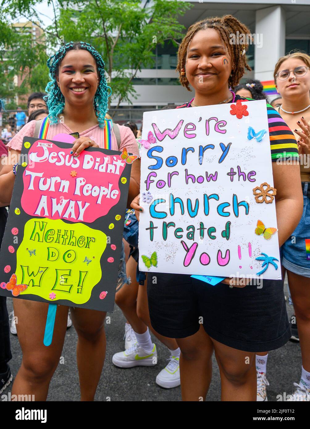 Two Christian women holding signs in support of the LGBTQ+  community during the Pride Parade Stock Photo