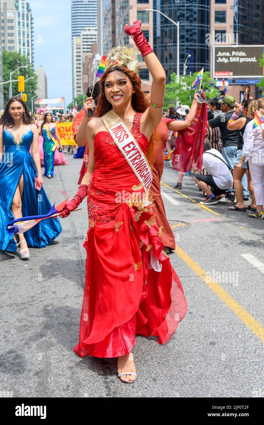A woman in a red dress and a sign reading Miss Extravaganza walks in Bloor Street as part of the Pride Parade Stock Photo