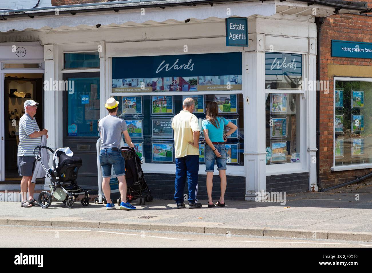 Man with a pushchair stroller and couple looking at an estate agents window, wards, tenterden, kent, uk Stock Photo