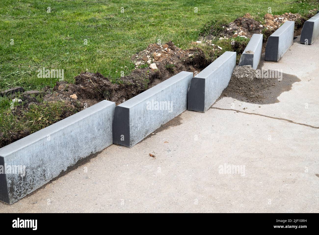 New curbs stand at the edge of the sidewalk. Preparing to repair the road Stock Photo