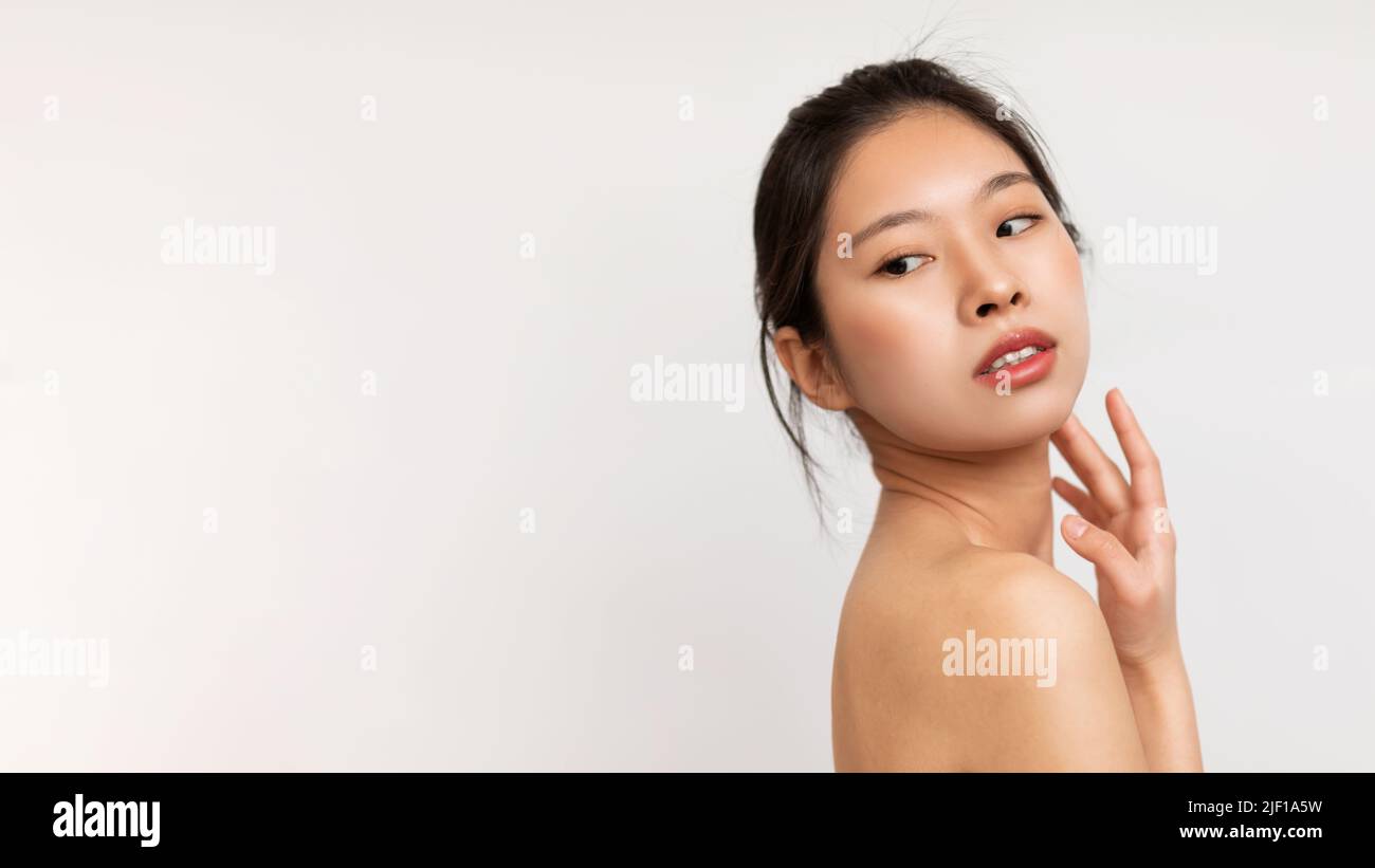 Face care concept. Portrait of young sensual asian lady looking back at copy space over white background, copy space Stock Photo