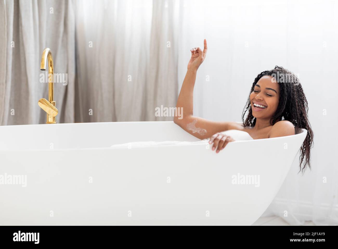 Carefree Black Lady Singing And Having Fun While Relaxing In Bathtub Stock Photo