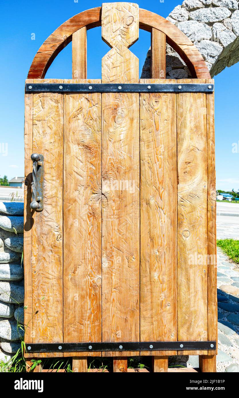 Massive handmade rough wooden door with metal handle close up Stock Photo