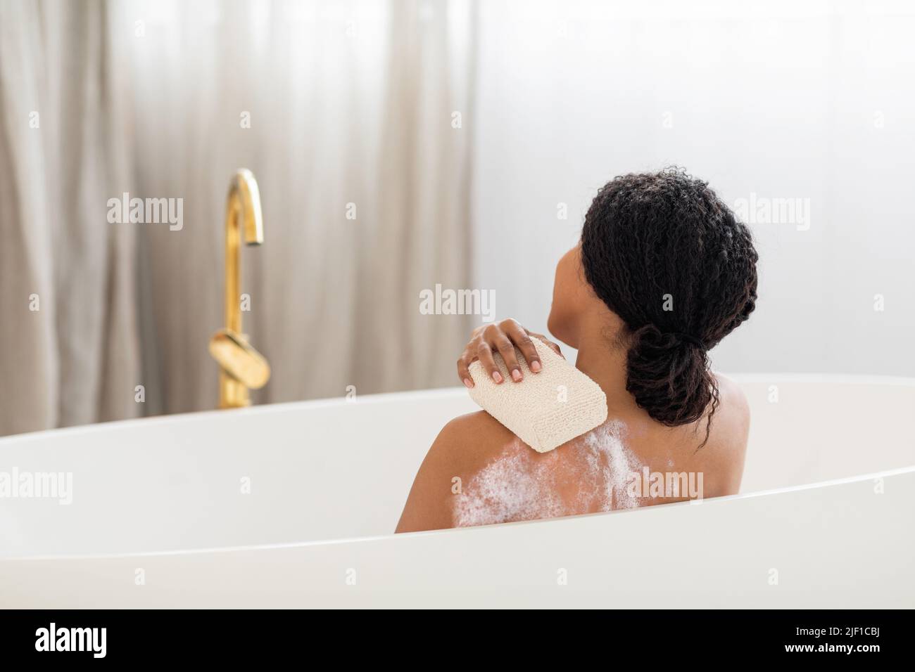 Young Black Lady Washing Herself With Sponge While Taking Bath At Home Stock Photo