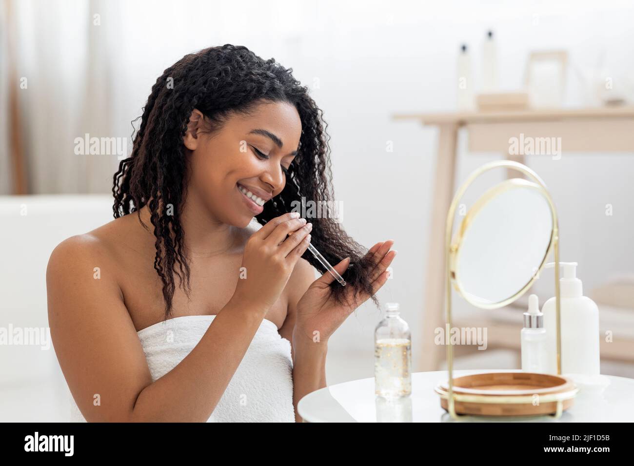 Happy Black Lady Applying Moisturising Oil On Damaged Hair Ends After
