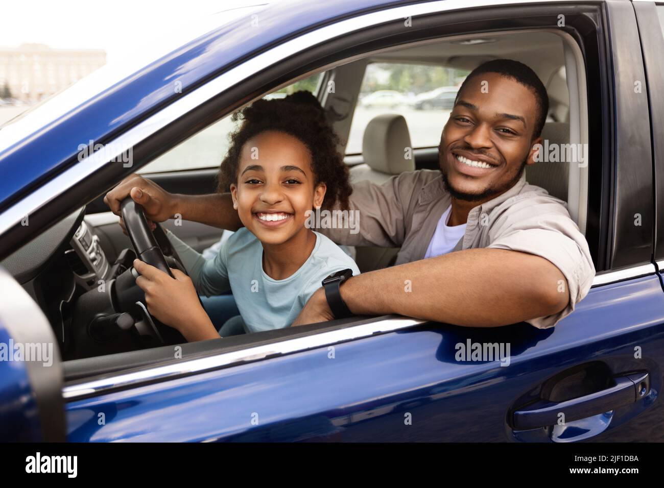 Black Daddy Teaching Preteen Daughter To Drive Smiling To Camera Stock Photo