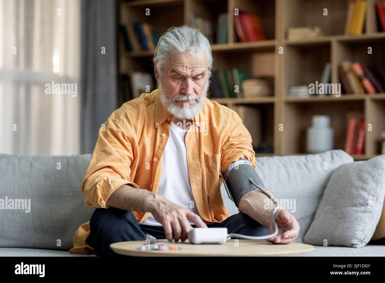 Handsome senior man checking blood pressure at home Stock Photo