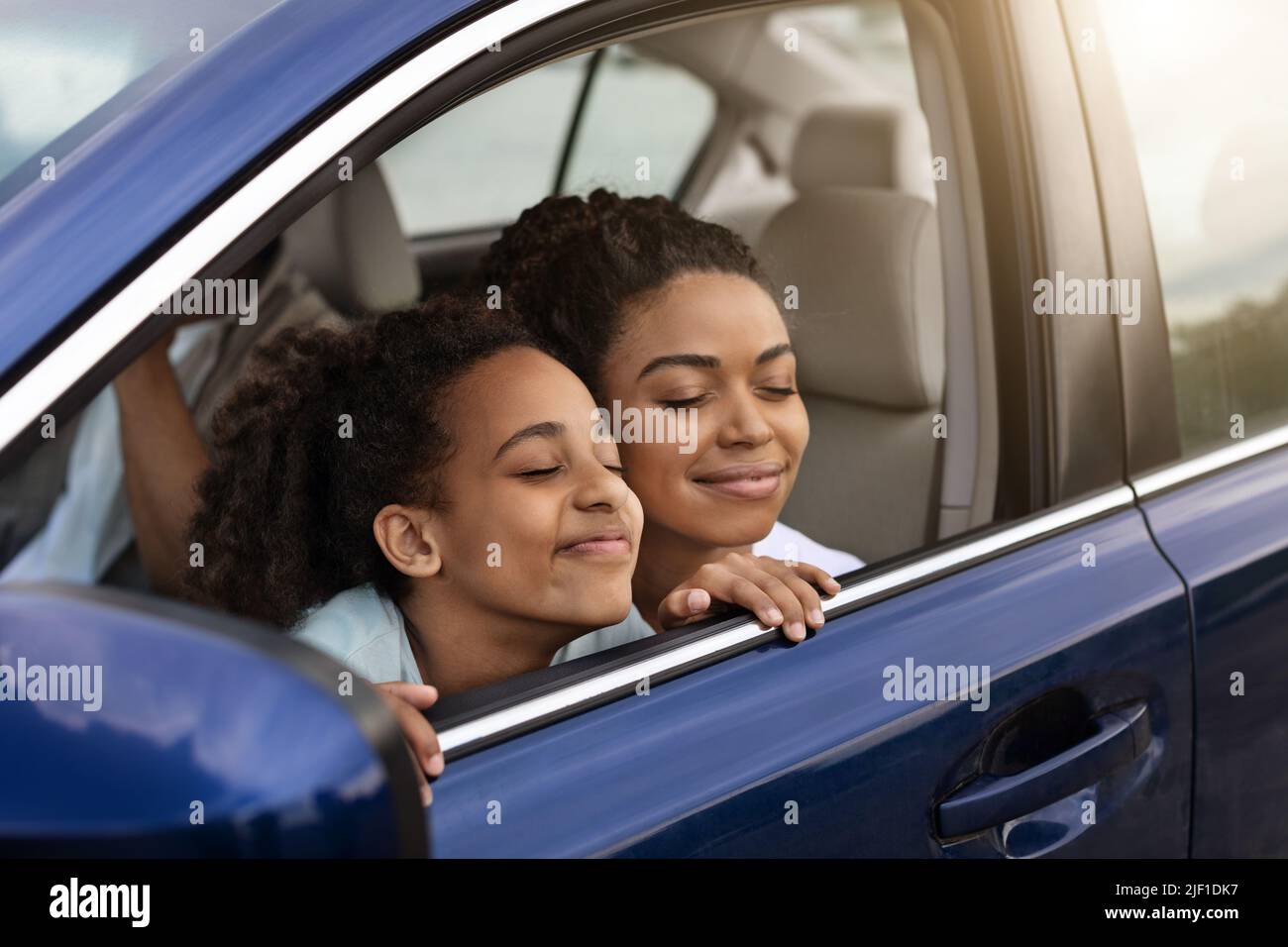 Joyful Black Mother And Daughter Sitting In Automobile Enjoying Trip Stock Photo