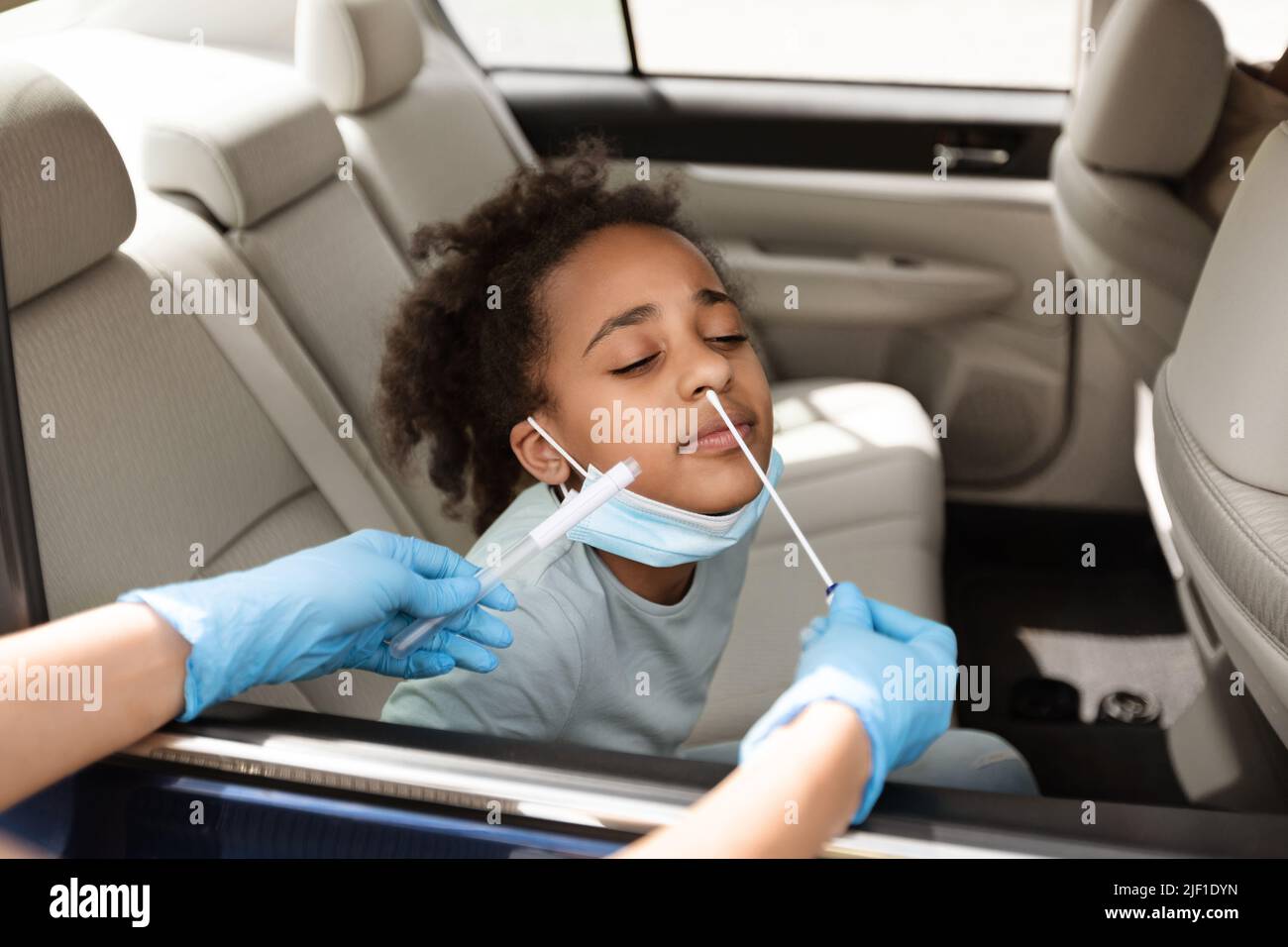 Black Preteen Girl Getting Tested For Covid-19 Sitting In Car Stock Photo
