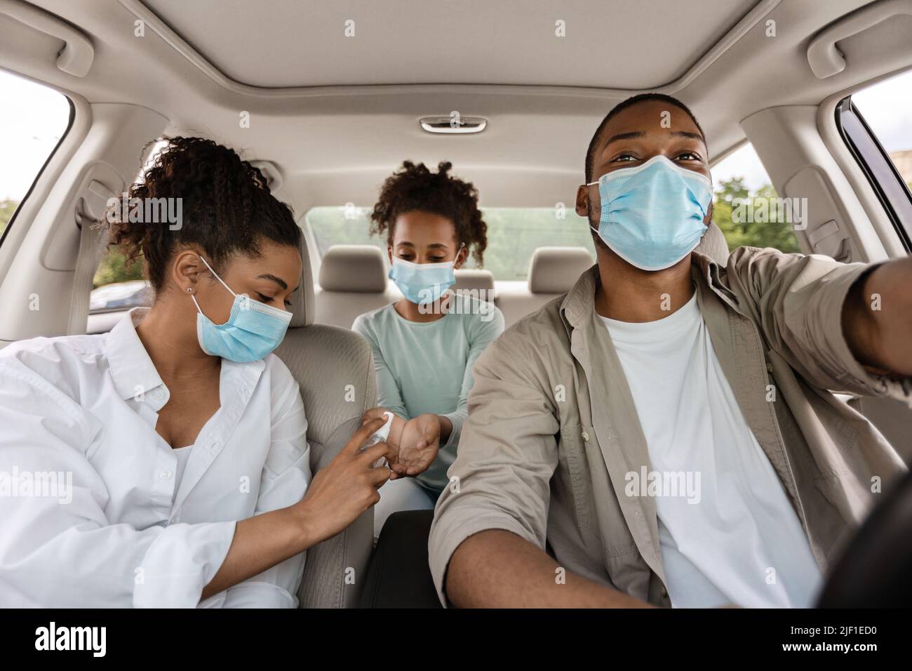 Black Family Using Sanitizer Wearing Face Masks Traveling By Car Stock ...