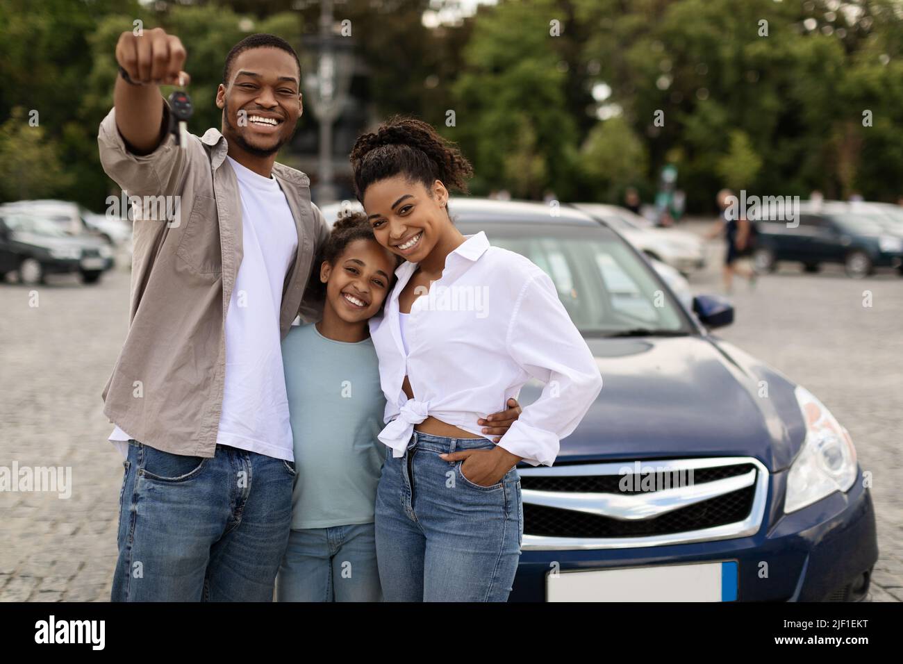 Joyful Black Family Showing Car Key Standing Near Auto Outdoor Stock Photo