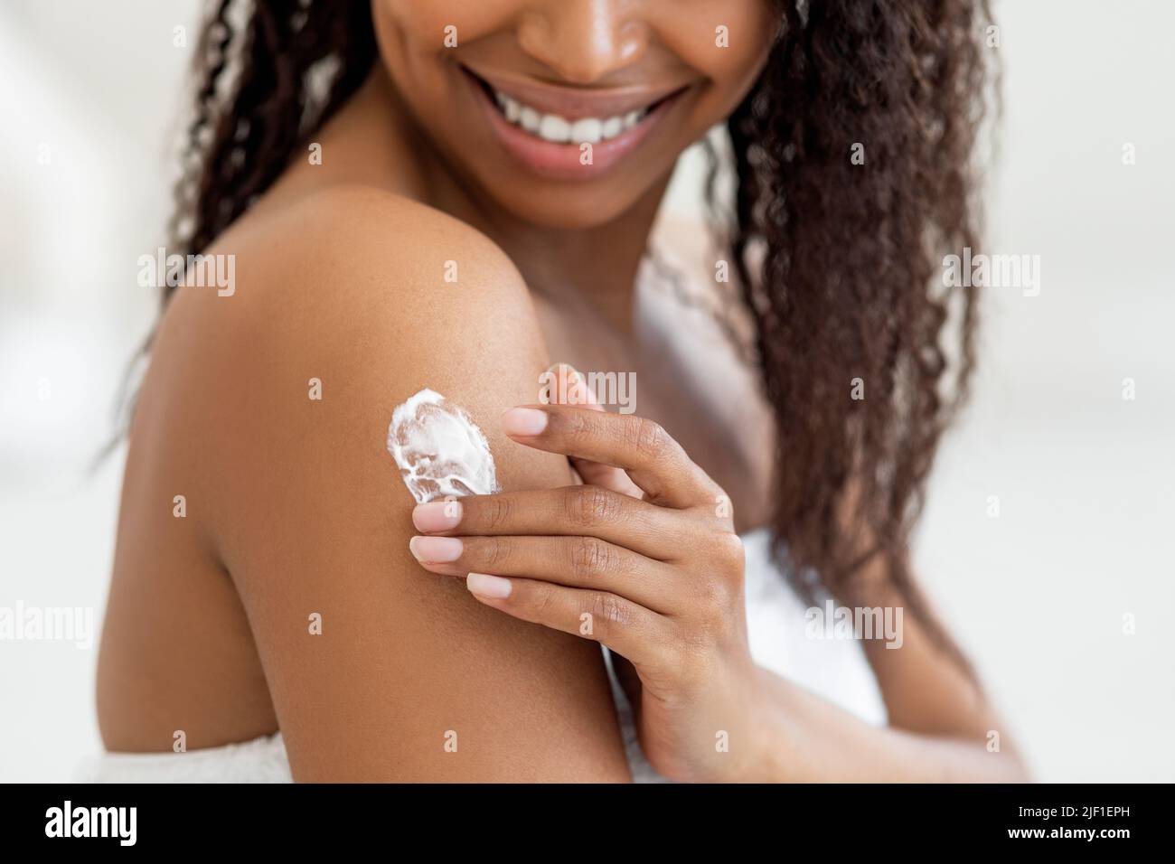 Closeup Shot Of Young Black Female Rubbing Moisturising Lotion To Skin Stock Photo