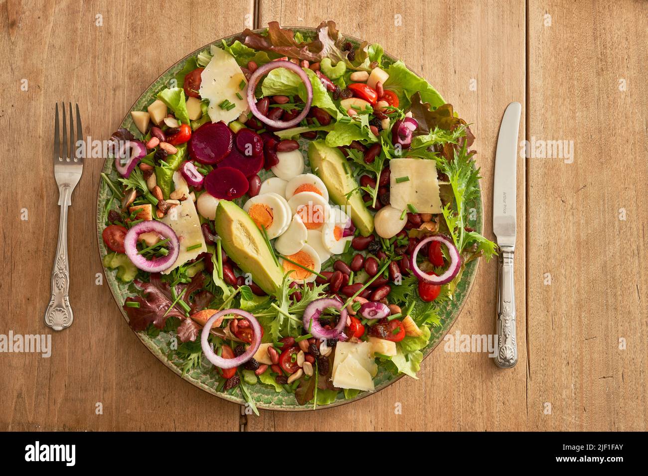 Green plate of healthy salad with knife and fork Stock Photo