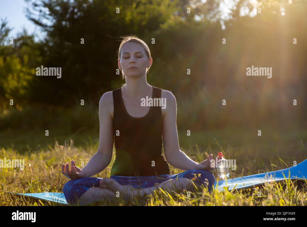 Young woman in lotus position on green grass. The concept of peace and meditation. Stock Photo