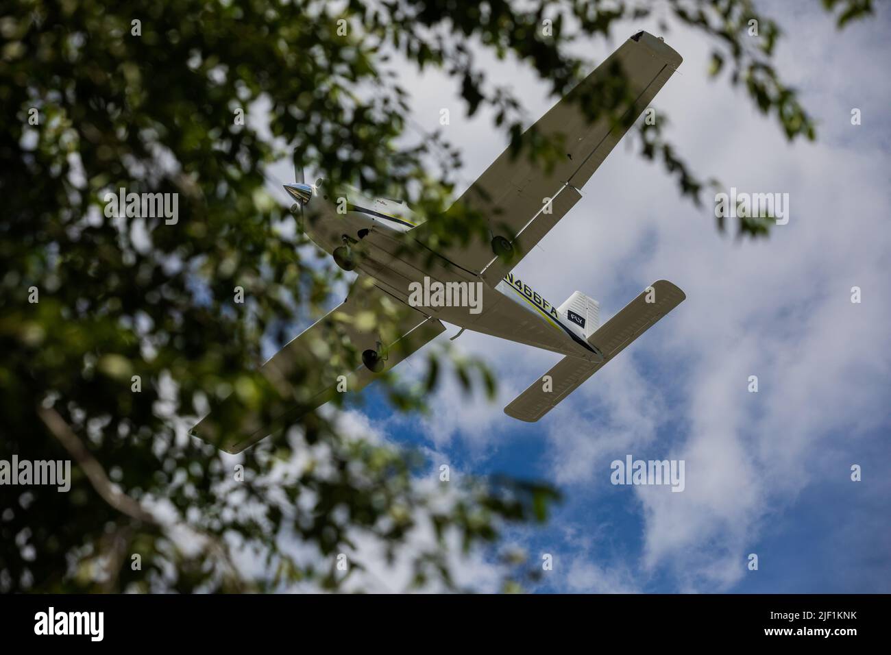 Small Plane Flies Overhead on Sunny Summer Day Stock Photo