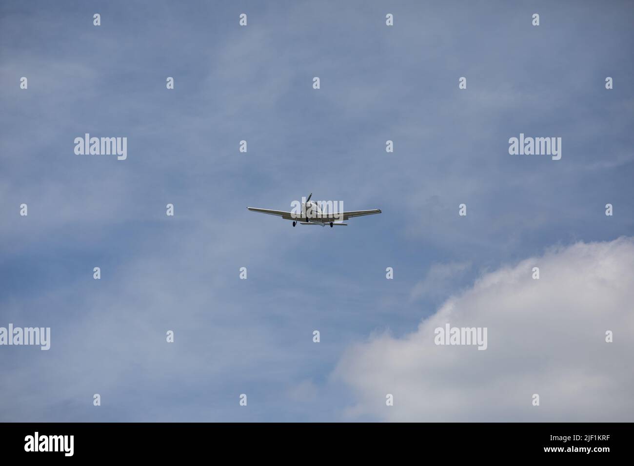 Small Plane Flies Overhead on Sunny Summer Day Stock Photo