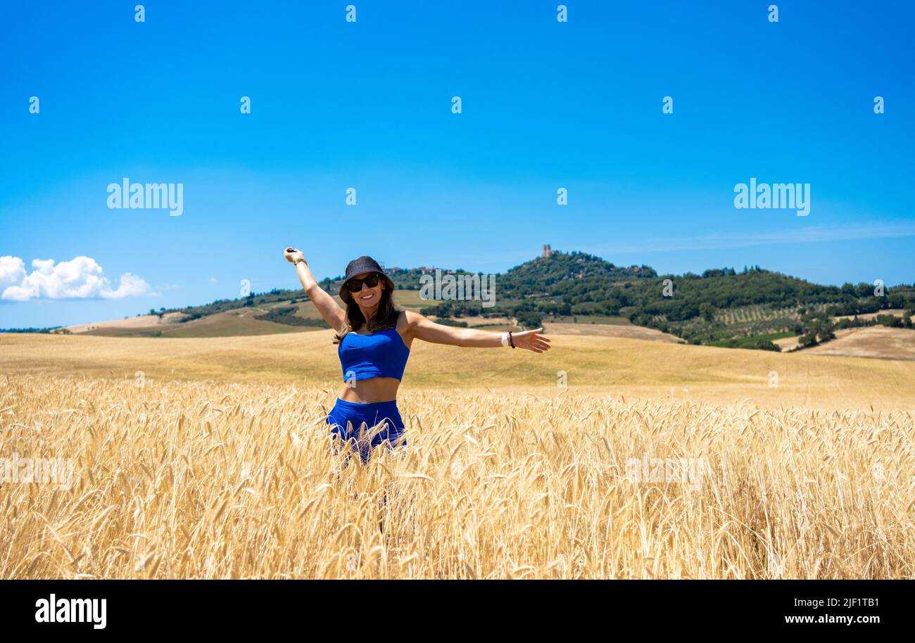 Girl walking through wheat fields in Tuscany Stock Photo