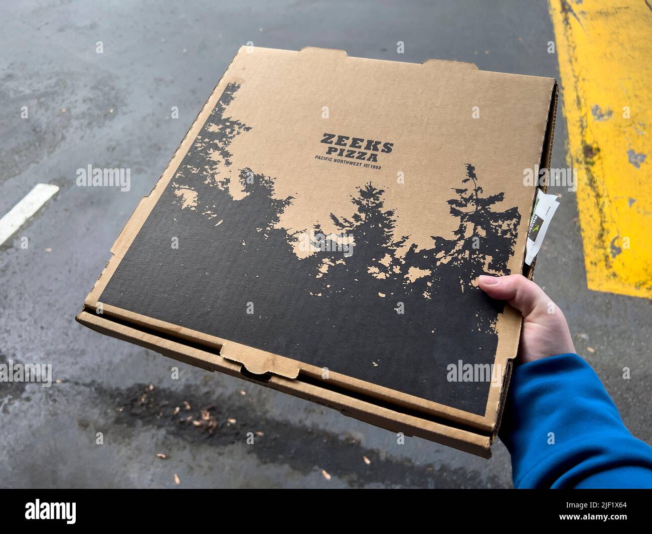 Seattle, WA USA circa May 2022 Close up view of someone holding a Zeek's pizza box in a