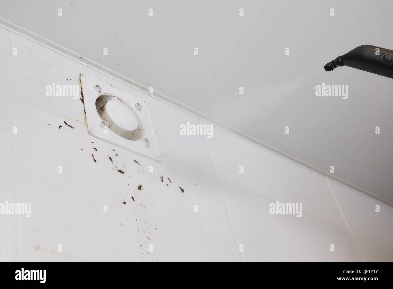 A man wipes dust from a ventilation grill technician cleaning air Stock