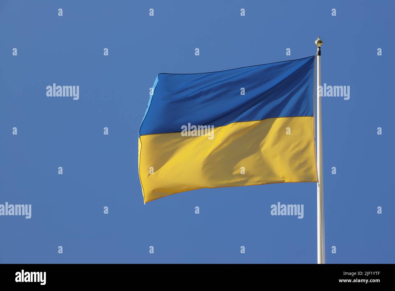 Close-up view of the Ukraine national flag against a blue clear sky. Stock Photo