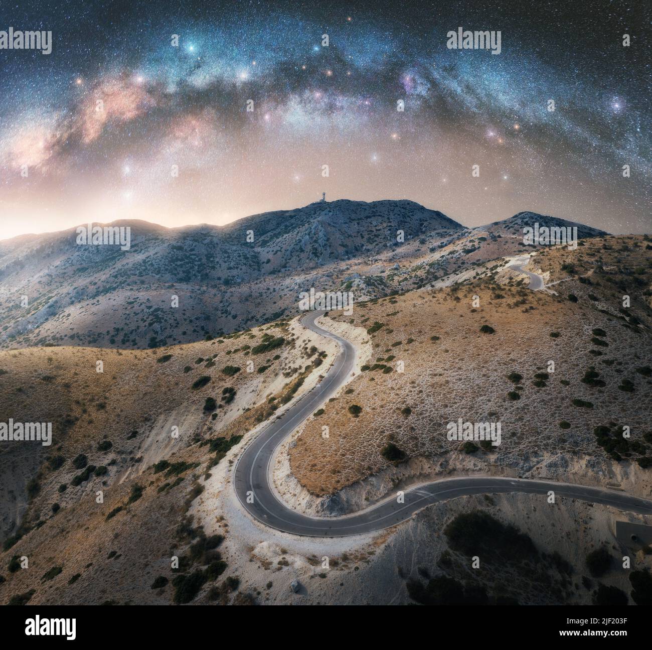 Milky Way arch and winding mountain road at night Stock Photo