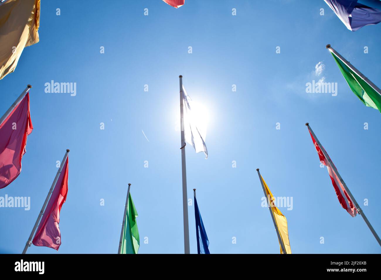 A low angle shot of a round of colorful flags on poles in a blue sky ...