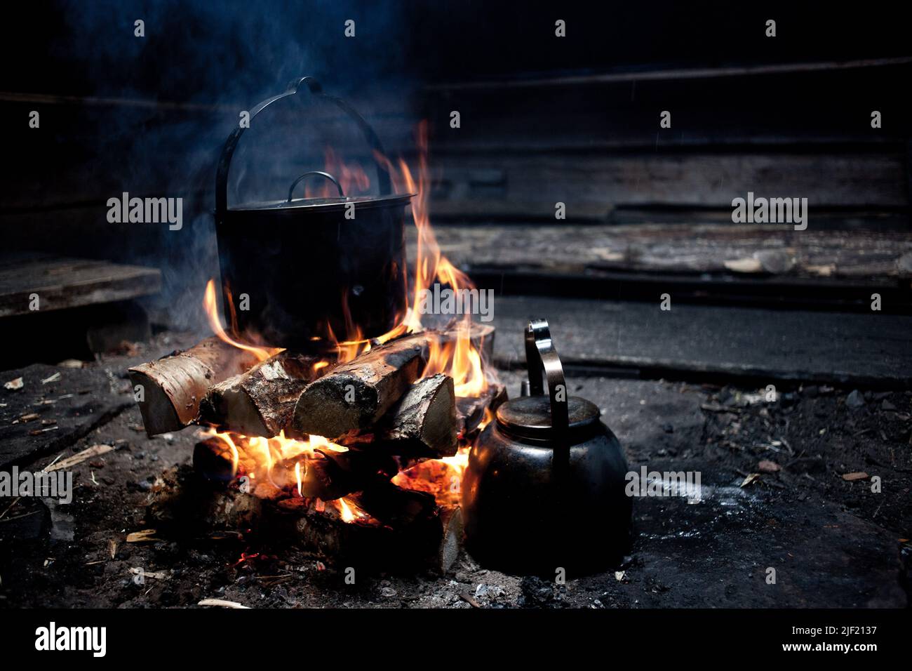 https://c8.alamy.com/comp/2JF2137/a-closeup-shot-of-a-pot-on-burning-firewood-and-a-tea-kettle-on-a-camp-site-2JF2137.jpg