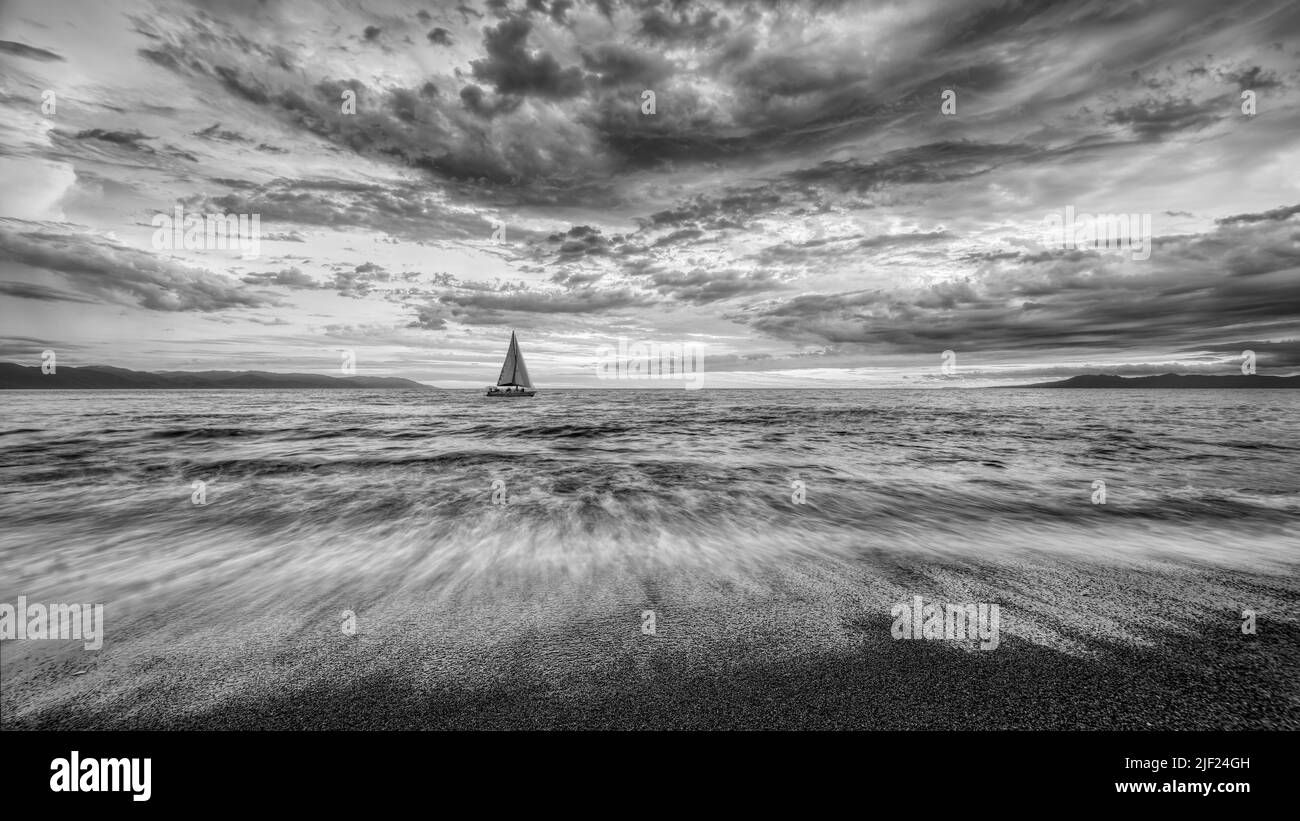 Detailed Clouds Are Overhead As A Small Boat Moves Toward The Shining Light Black And White 16.9 Stock Photo