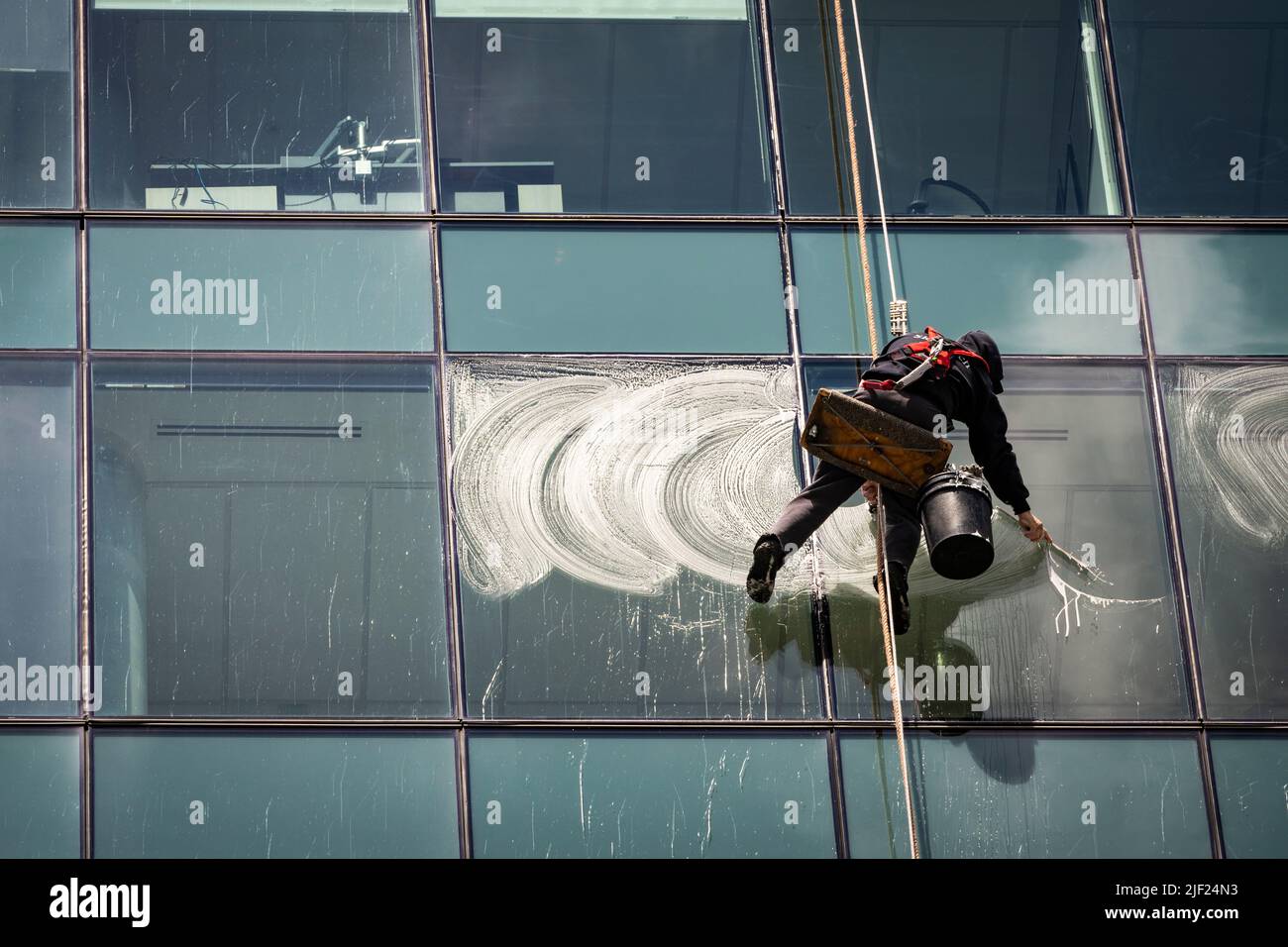 Window cleaners working while suspended from the top of the building