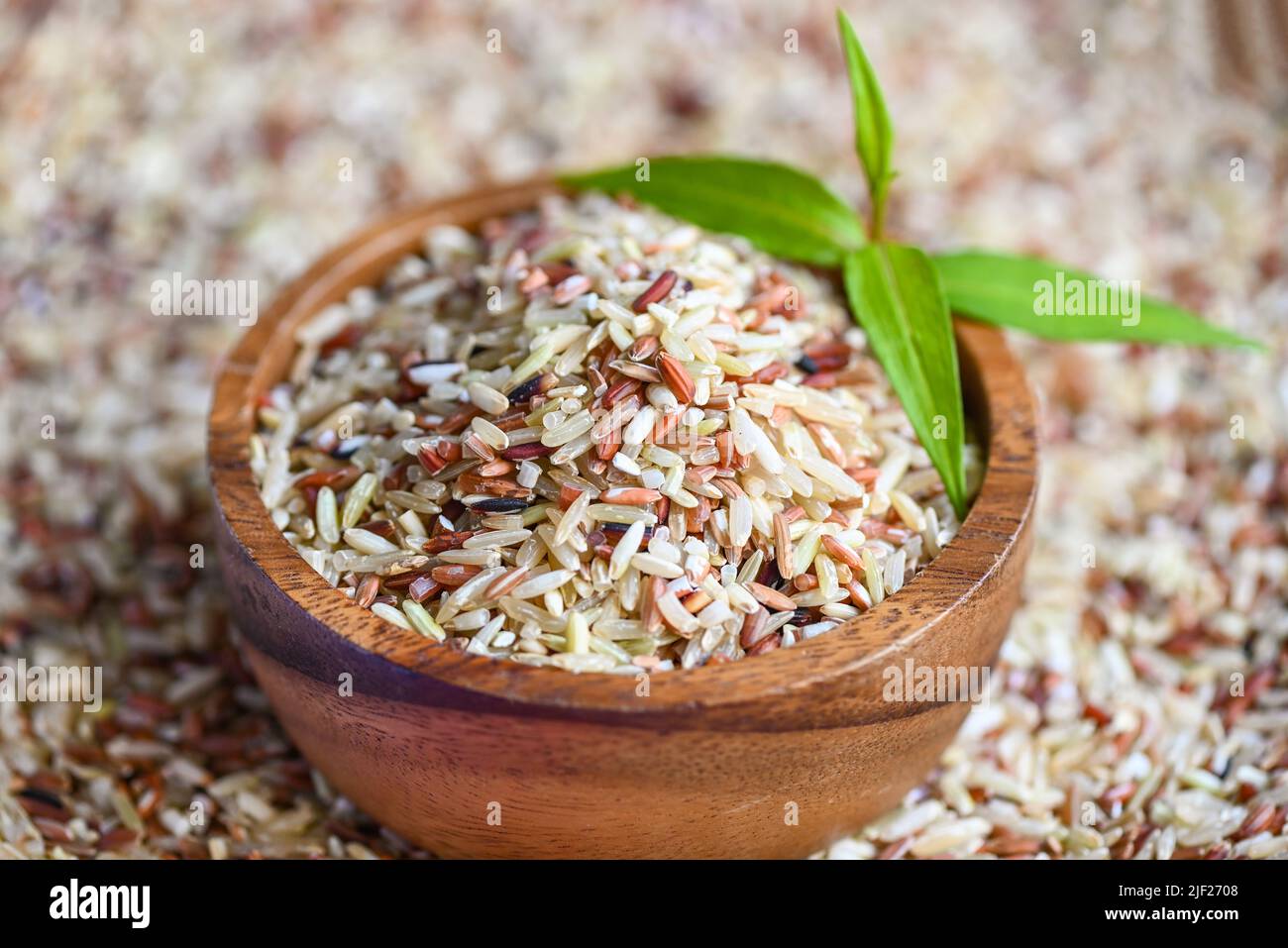 brown rice on wooden bowl and green leaf, raw various rice color mixed ...