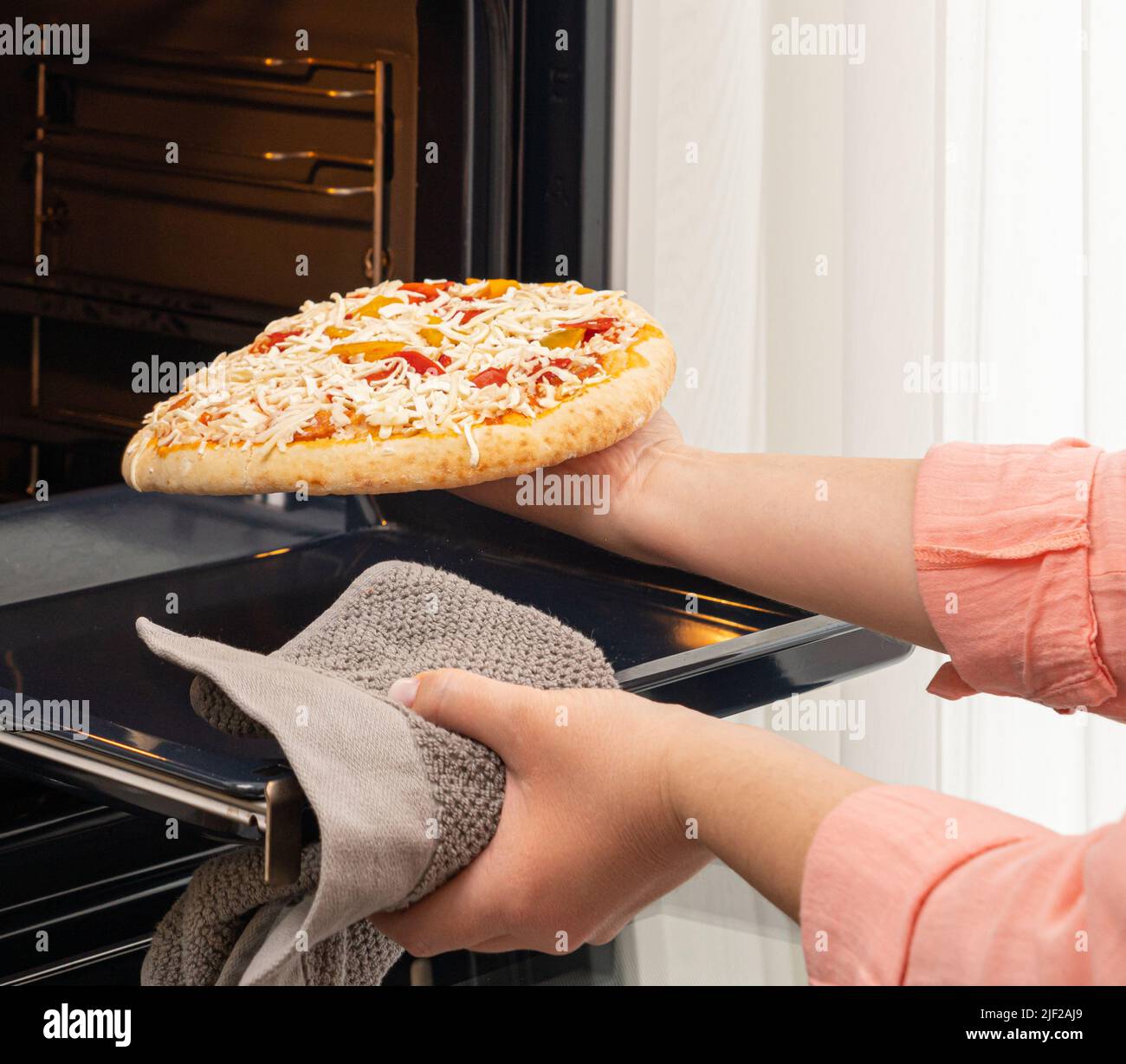 The girl puts the pizza in the oven for baking Stock Photo Alamy