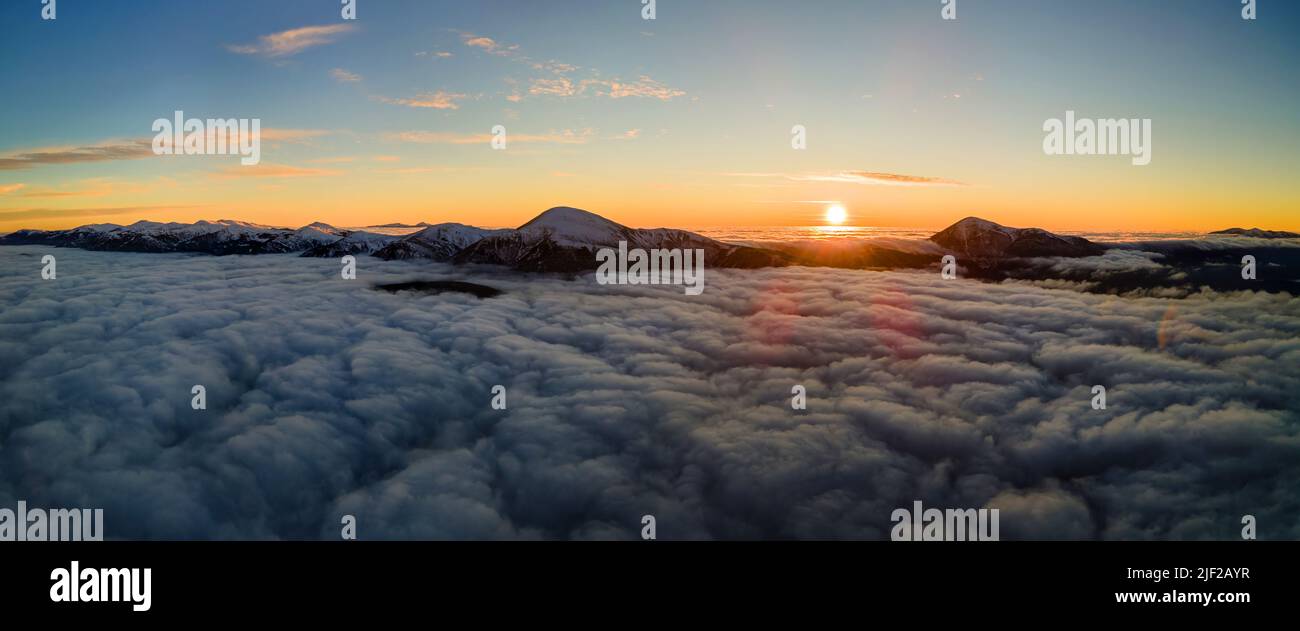 Aerial view of vibrant sunrise over white dense clouds with distant ...