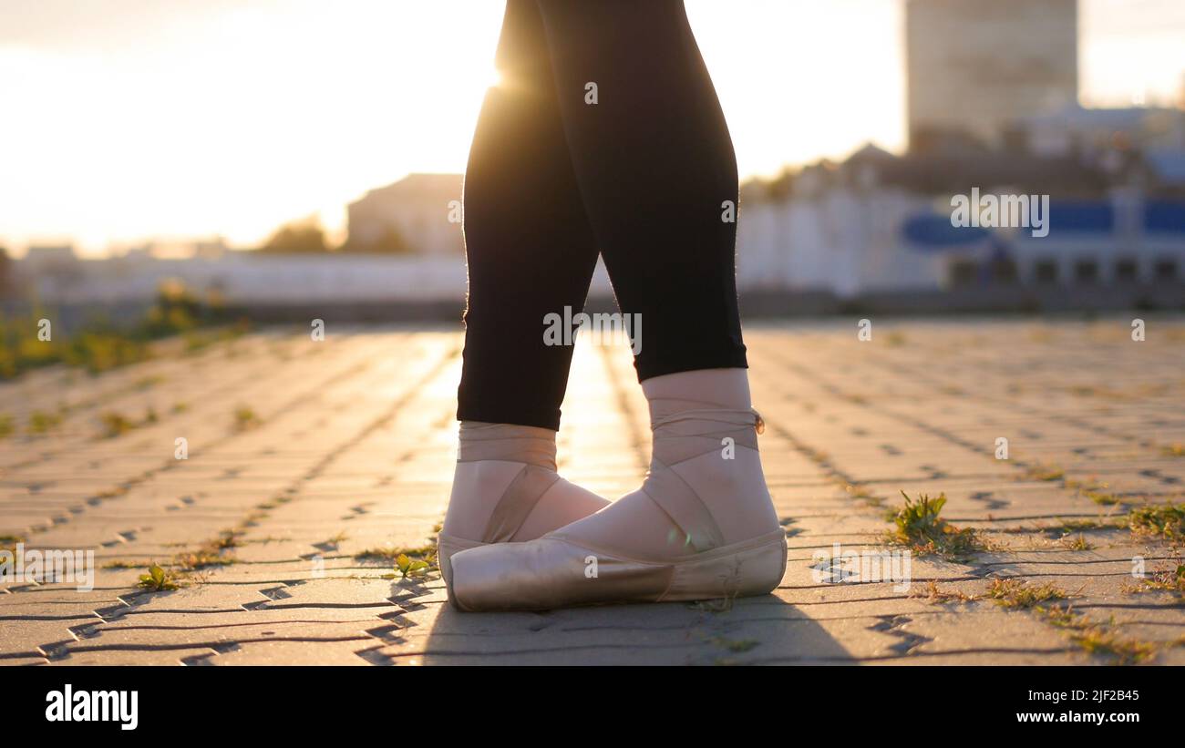 Legs of young woman ballerina standing in the classic stand on the full feet - sunset Stock Photo