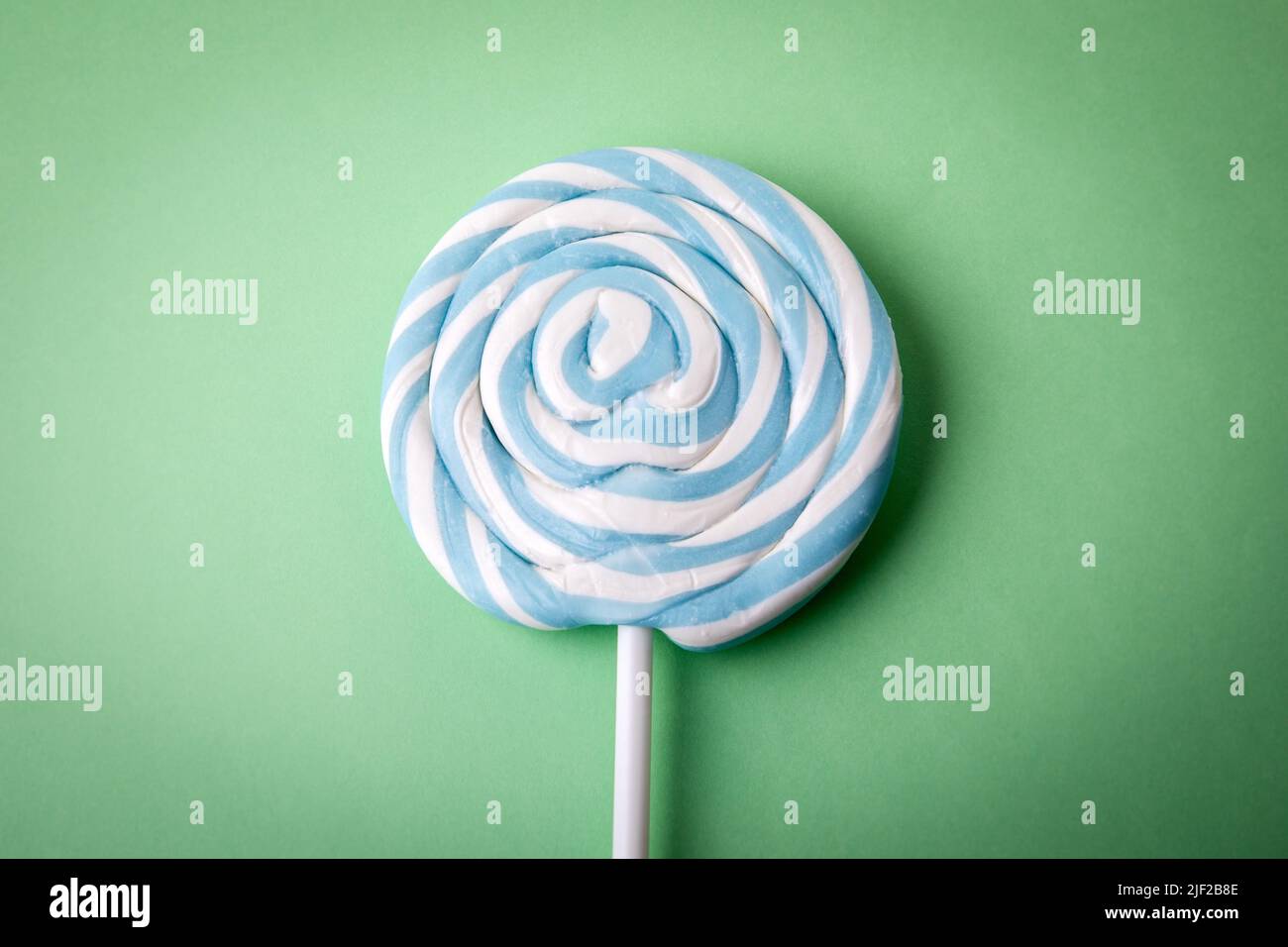 Brightly colored candy, lollipop on a stick. Green background. Stock Photo