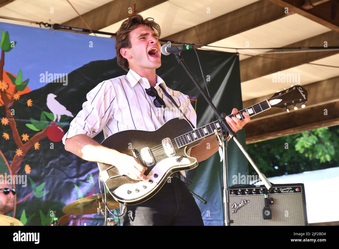 Musician Jake Manzi shown performing on stage during a “live” concert ...