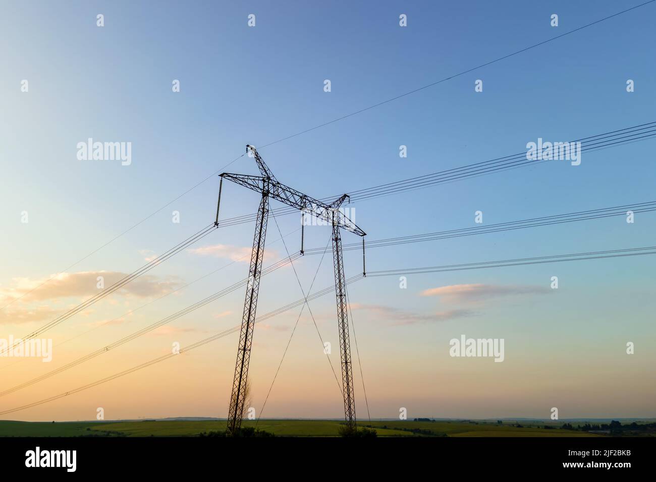 Dark silhouette of high voltage towers with electric power lines at ...