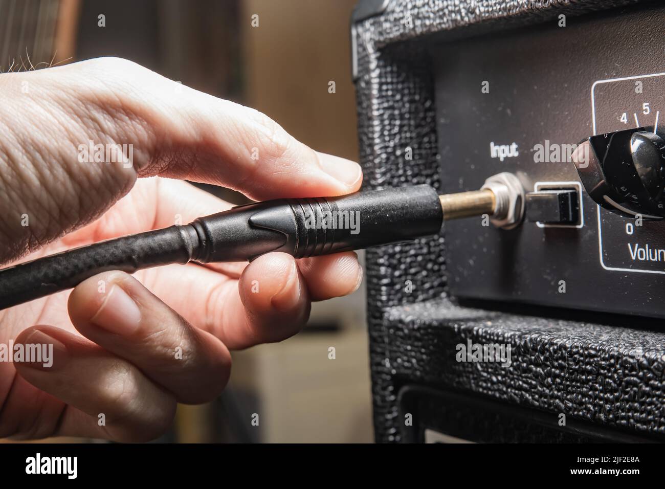 Plugging an instrument cable into a guitar amplifier Stock Photo