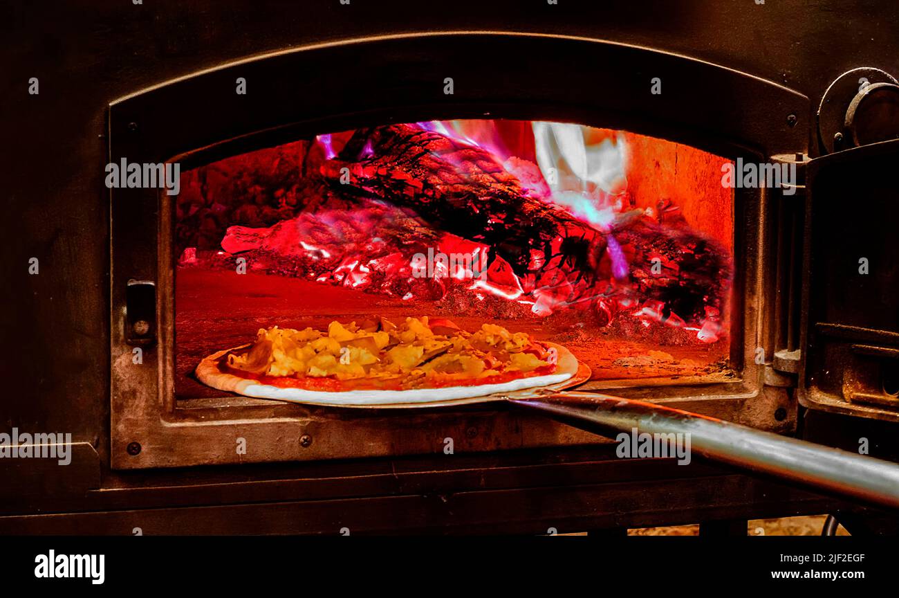 Woodfired pizza oven. Closeup of a pizza direct putting in to bake in
