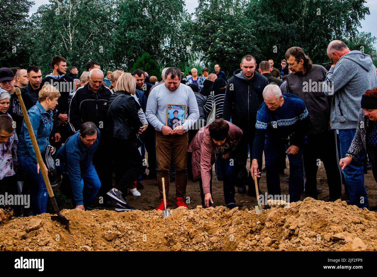 Brother of Sergey Titov is crying, while the mourners throw soil over