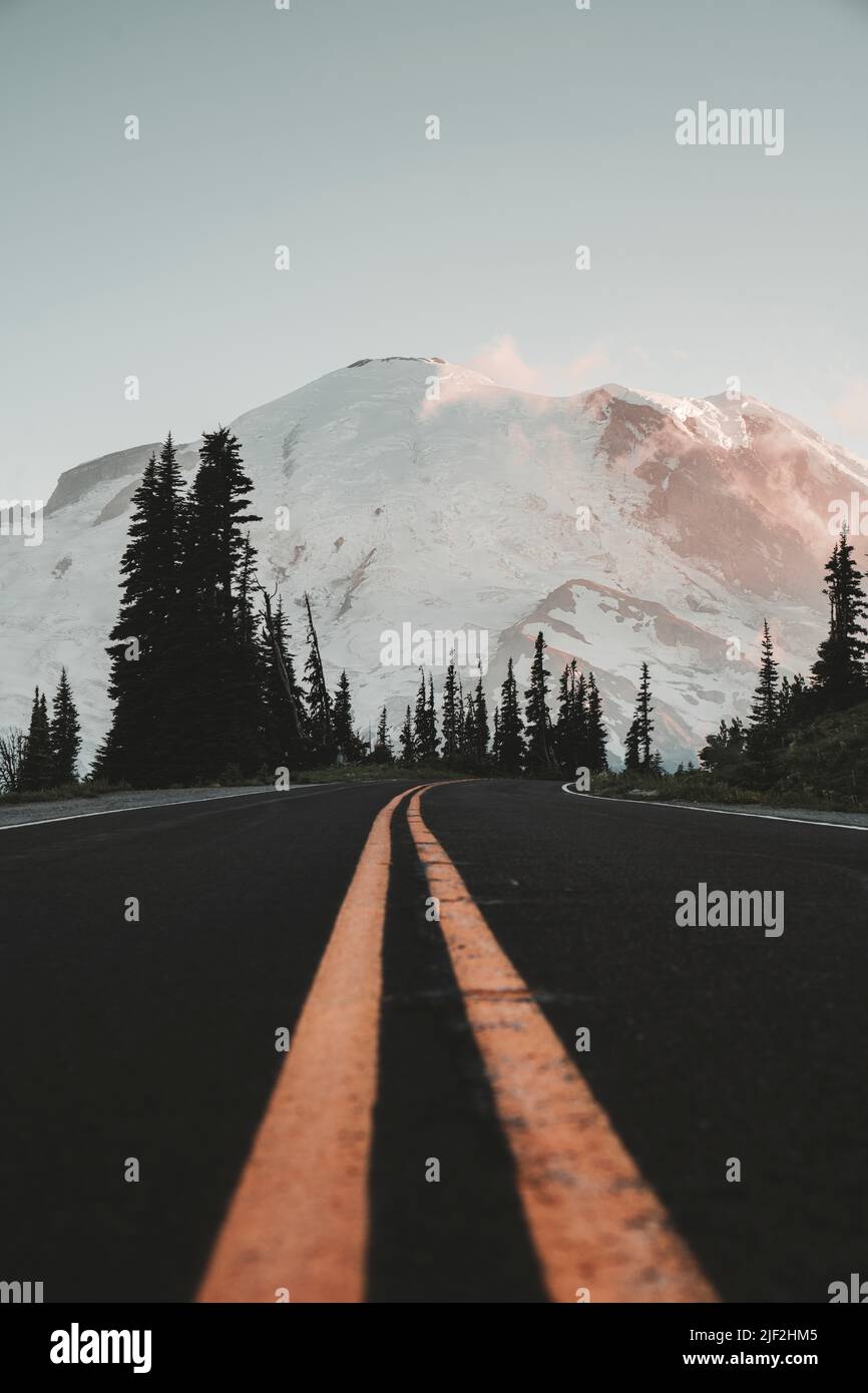 The close-up of asphalt yellow line road with snowy mountain background at Sunrise Park at Mt. Rainier in Washington Stock Photo